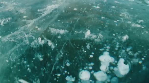 Товстий шар синьої замороженої води з бульбашками і тріщинами на озері — стокове відео