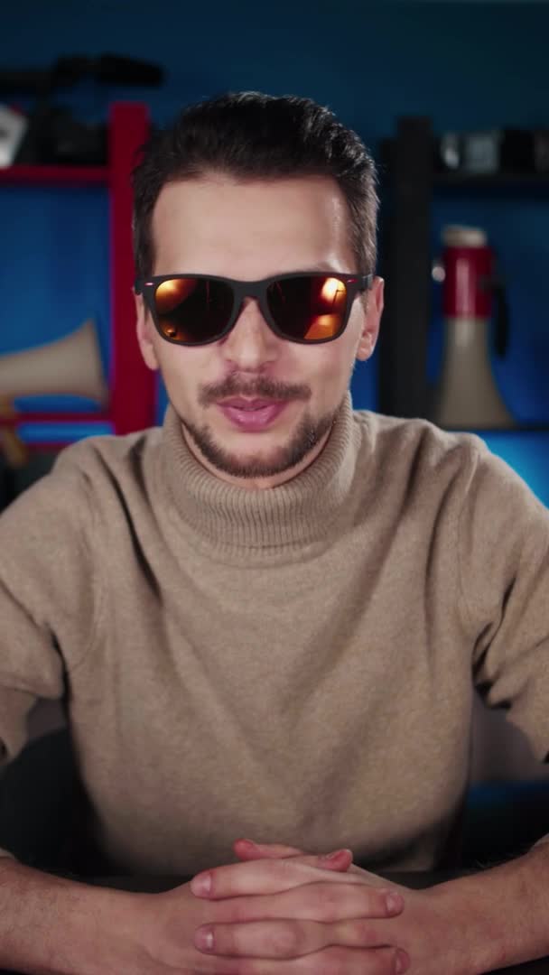 선글라스를 쓴 유럽 남자 가 스튜디오에 있는 테이블에 앉아 — 비디오