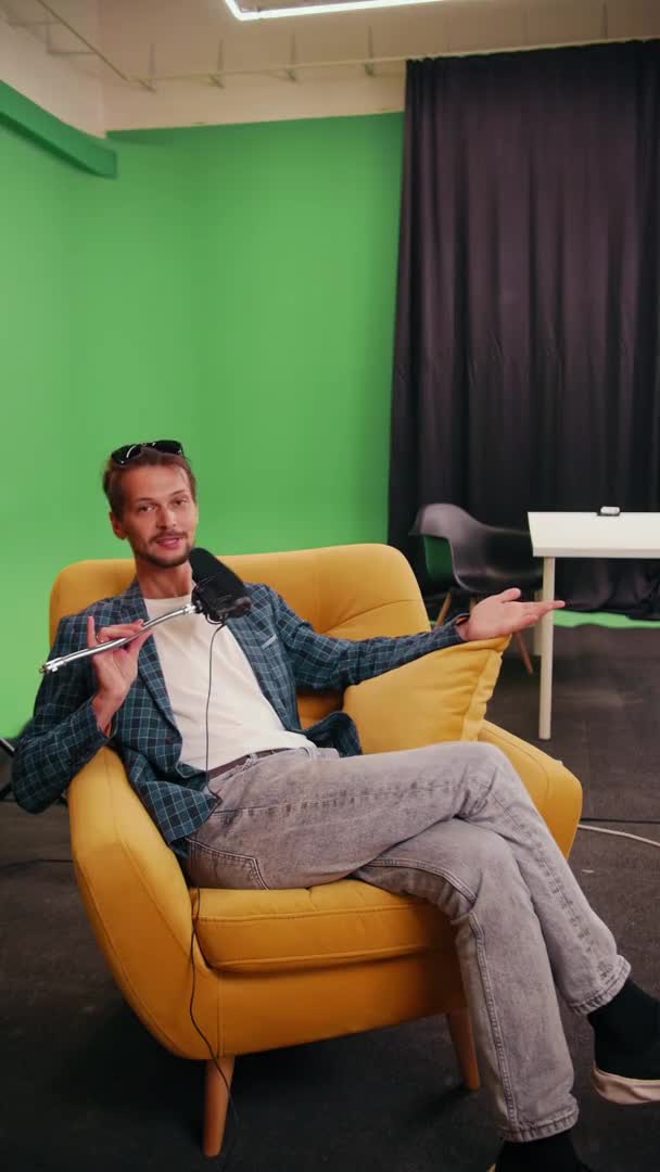Καυκάσιος blogger βίντεο κάθεται σε μια κίτρινη καρέκλα στο στούντιο μιλώντας — Αρχείο Βίντεο