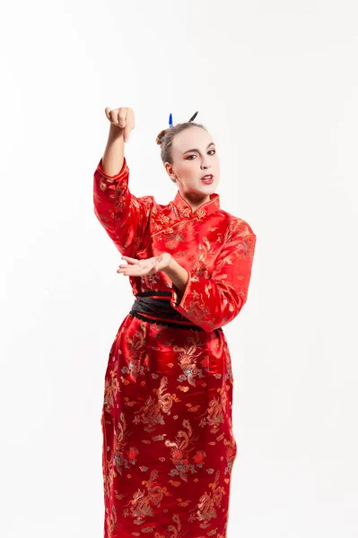 Geleneksel kırmızı Çin kostümü giymiş, beyaz makyajlı, saçı kalemle tutturulmuş, hayali bir iplikle kolunu kaldıran genç bir kadın. Doğu konsepti ve tiyatro.