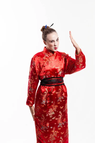 Kırmızı doğulu genç adam, kameraya bakıyor ve burnunu kırıştırıyor ve beyaz arka plana karşı kınama olarak kolunu kaldırıyor.