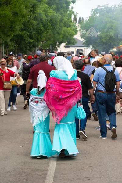 Madrid, İspanya; 15 Mayıs 2022: Saint Isidro fuarındaki tezgahları ziyaret eden bir grup insan. Anne ve kızı sırtlarını dönerek geleneksel Madrid Chulapas kostümü giydiler.