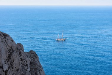 Horizontal view from a sailboat gorge with a turquoise Mediterranean Sea and blue sky on the horizon.
