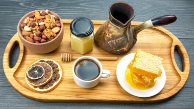 Hindi ve kurutulmuş turunçgil, fındık ve bal peteği ile birlikte mutfak tahtasının üzerinde taze kahve. İnsan vücudu için yararlı vitamin yiyeceği