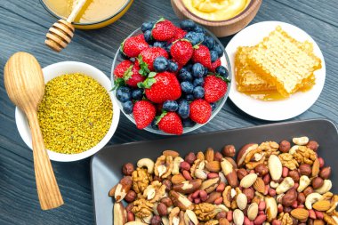 Tahta arka planda taze bal, fındık, çilek ve yaban mersini. sağlıklı organik vitamin yiyeceği.