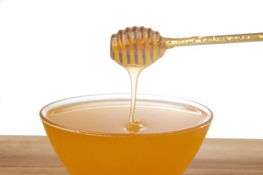 Beyaz arka planda şeffaf bir plakaya damlayan taze bal. organik vitamin sağlıklı gıdalar