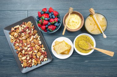 Tahta arka planda taze bal, fındık, çilek ve yaban mersini. sağlıklı organik vitamin yiyeceği.