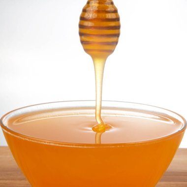 Beyaz arka planda şeffaf bir plakaya damlayan taze bal. organik vitamin sağlıklı gıdalar