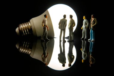 Minyatür insanlar. biblolar insanlar içinde LED lamba yakın durur.