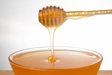 Beyaz arka planda şeffaf bir plakaya damlayan taze bal. organik vitamin sağlıklı gıdalar