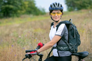 Güzel ve mutlu bir kadın bisikletçi doğada bisiklet sürüyor. Sağlıklı yaşam tarzı ve spor. Boş zaman ve hobiler.