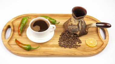 Kahve çekirdekli tahtanın üzerinde beyaz bir fincanda taze demlenmiş siyah kahve. acı biber ve limon