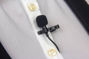 Bir kadının gömleğine takılmış mandallı ses kaydı için küçük bir mikrofon..