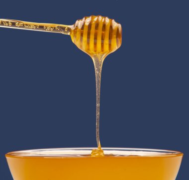 Taze kokulu bal renkli bir arka planda kaşıktan bir plakaya damlıyor. Organik vitamin besin. Tatlı yemek.