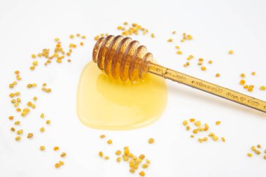 Beyaz arka plana taze bal ve polen dökülmüş kaşık. organik vitamin yiyeceği