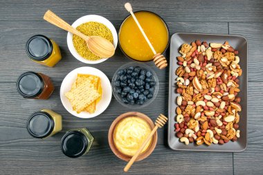 Tahta arka planda taze bal, fındık, çilek ve yaban mersini. sağlıklı organik vitamin yiyeceği.