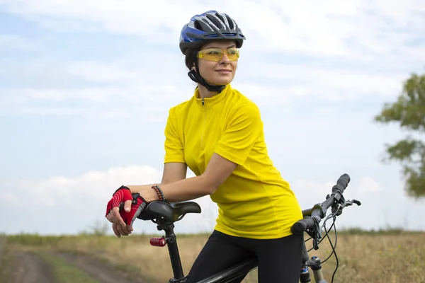 美しく幸せな女性サイクリストが自然界の道路を自転車で走っています 健康的なライフスタイルとスポーツ — ストック写真