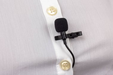 Lavalier mikrofon bir kadın gömleğinin yakın plan klipsiyle korunuyor. Yoğunlaştırıcı mikrofondaki sesin ses kaydı.
