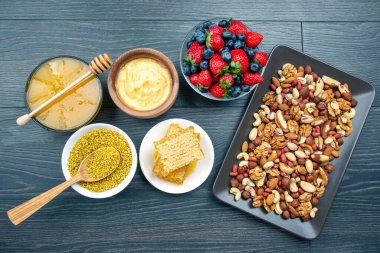 Tahta arka planda taze bal, fındık, çilek ve yaban mersini. sağlıklı organik vitamin yiyeceği.