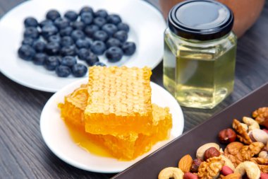 Tahta arka planda taze bal, fındık, çilek ve yaban mersini. sağlıklı organik vitamin yiyeceği.