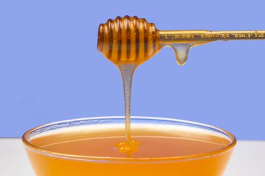 Taze kokulu bal renkli bir arka planda kaşıktan bir plakaya damlıyor. Organik vitamin besin. Tatlı yemek.