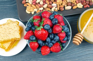 Tahta arka planda taze bal, fındık, çilek ve yaban mersini. sağlıklı organik vitamin yiyeceği.