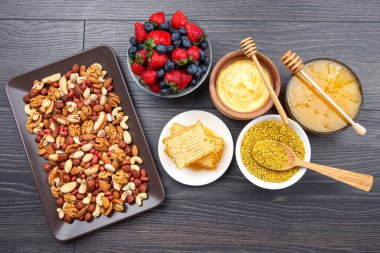 Tahta arka planda taze bal, fındık, çilek ve yaban mersini. sağlıklı organik vitamin yiyeceği.