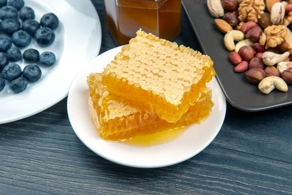 Tahta arka planda taze bal, fındık ve yaban mersini. sağlıklı organik vitamin yiyeceği.