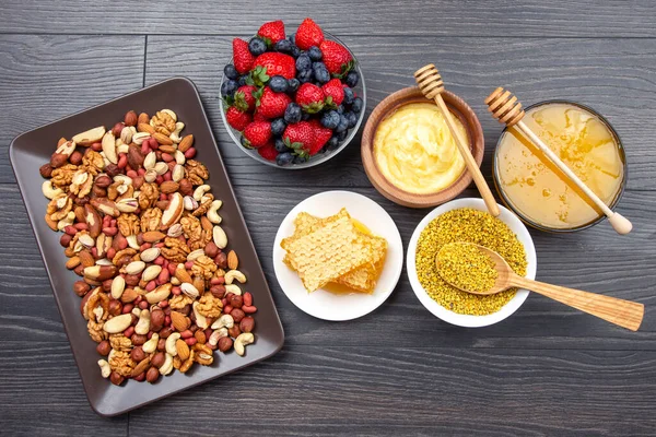 Tahta arka planda taze bal, fındık, çilek ve yaban mersini. sağlıklı organik vitamin yiyeceği.