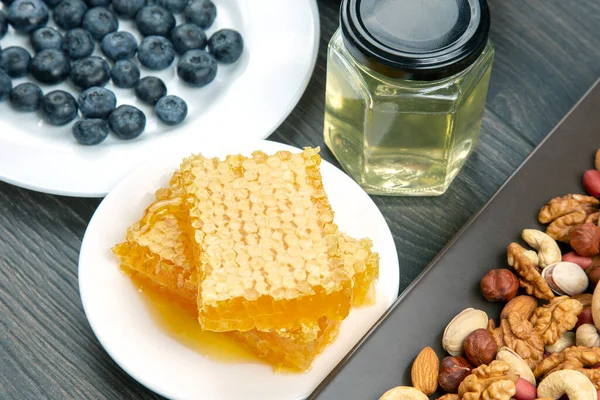 Tahta arka planda taze bal, fındık ve yaban mersini. sağlıklı organik vitamin yiyeceği.