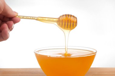 Beyaz arka planda şeffaf bir plakaya damlayan taze bal. organik vitamin sağlıklı gıdalar