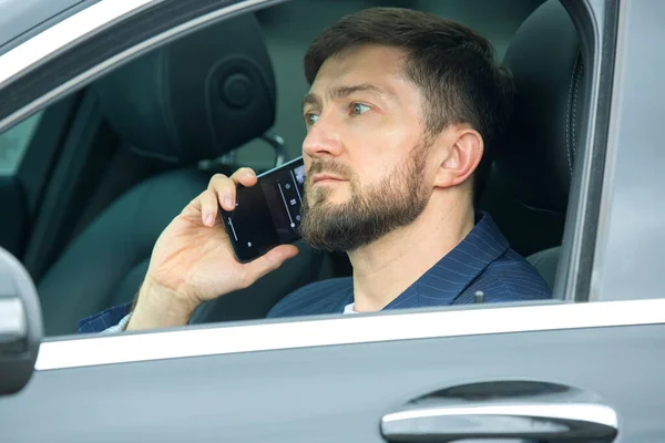 Udany Biznesmen Telefonem Ręku Siedzi Kierownicą Prestiżowego Samochodu — Zdjęcie stockowe