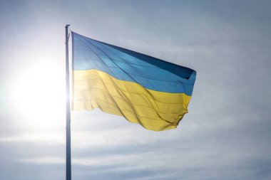 Ukrayna 'nın ulusal bayrağı güneş ve mavi gökyüzünün arka planına karşı. Vatanseverlik ve ulusal sembol