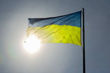 Ukrayna 'nın ulusal bayrağı güneş ve mavi gökyüzünün arka planına karşı. Vatanseverlik ve ulusal sembol