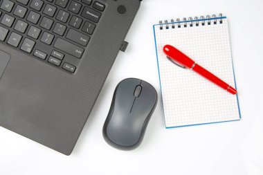Bilgisayar kablosuz fare, kalem ve not defteri beyaz bir masada yakın plan dizüstü bilgisayarın yanında. Ofis işleri için eşyalar