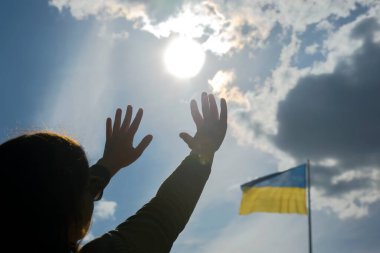 Ukrayna bayrağının arka planına karşı ellerini kaldır. Yardım için dua ve...