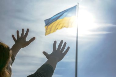 Ukrayna bayrağının arka planına karşı ellerini kaldır. Yardım için dua ve...