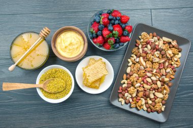 Tahta arka planda taze bal, fındık, çilek ve yaban mersini. sağlıklı organik vitamin yiyeceği.