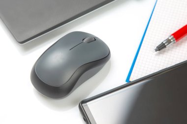 Bilgisayar kablosuz fare, kalem ve not defteri beyaz bir masada yakın plan dizüstü bilgisayarın yanında. Ofis işleri için eşyalar