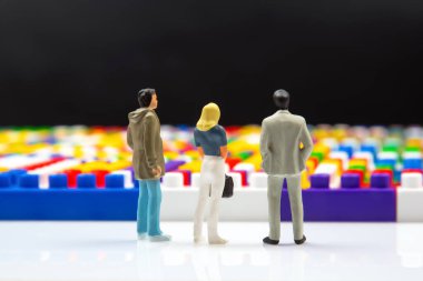 Minyatür insanlar. Tasarımcının renkli plastik bloklarının yanında duran insan figürleri. İş ve endüstriyel kalkınma kavramı. Rüya kavramı ve yaşam yönü seçimi.