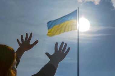 Ukrayna bayrağının arka planına karşı ellerini kaldır. Yardım için dua ve...