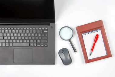 Laptop, büyüteç, bilgisayar faresi, akıllı telefon, kalem, beyaz arka planda not defteri. İş ve mal satın almak için internet üzerinden eşyalar