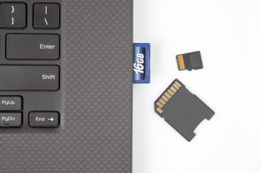SD hafıza kartı beyaz arka planda bir dizüstü bilgisayarın yanında elektronik veri kaydetmek için. elektronik sanayi ve bilgi ögeleri