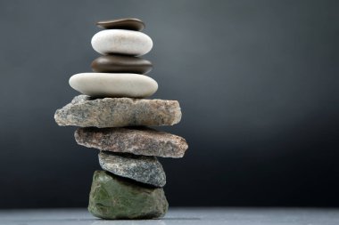 Karanlık bir arka planda istiflenmiş taş piramidi. Hayatta dengeleme ve denge