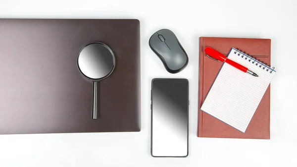 Laptop, magnifying glass, computer mouse, smartphone, pen, notepad on a white background. Items for business and buying goods online
