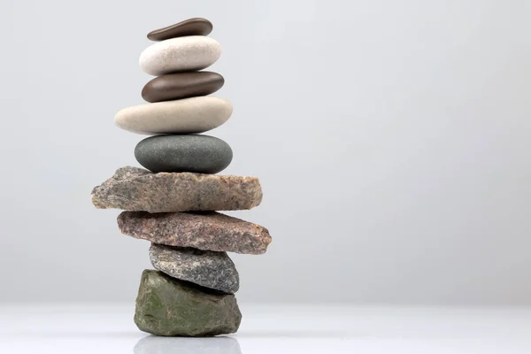 pyramid of stacked stones on a light background. stabilization and balance in life