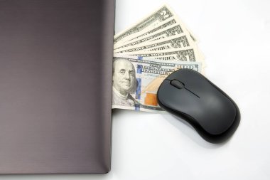Beyaz arka planda bir laptop ve bir bilgisayar faresinin yanında dolar banknotları. İnternetten iş satışı. Finansal iş başarısı.