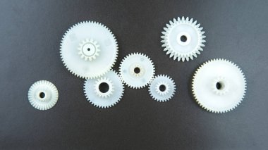 Siyah arka planda beyaz plastik dişliler. bağlantı mekanizması detayları. hareket konusu
