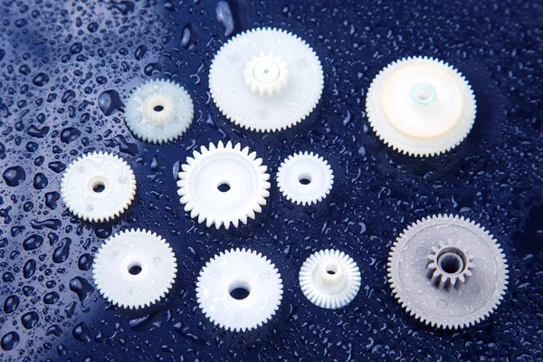 white plastic gears on a dark background. connection mechanism details. subject of movement