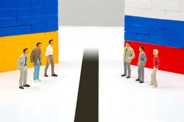 miniature people. Confrontation between two countries of peoples. National Ukrainian and Russian flag from colored blocks constructor. The problem of relations between countries. Russian aggression against Ukraine.